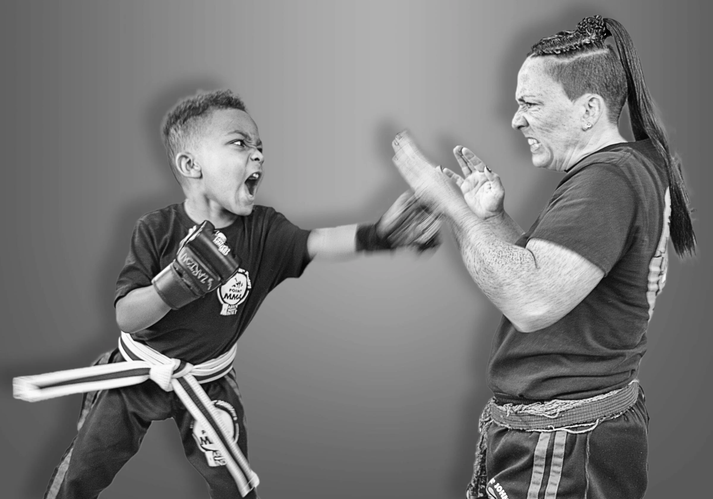 A coach holding pads for a young student throwing a punch